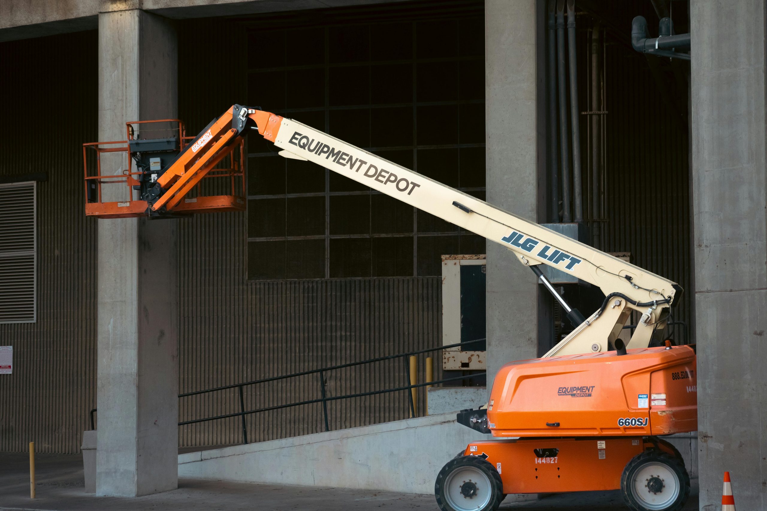 Orange JLG lift positioned at an industrial construction site, ready for use.